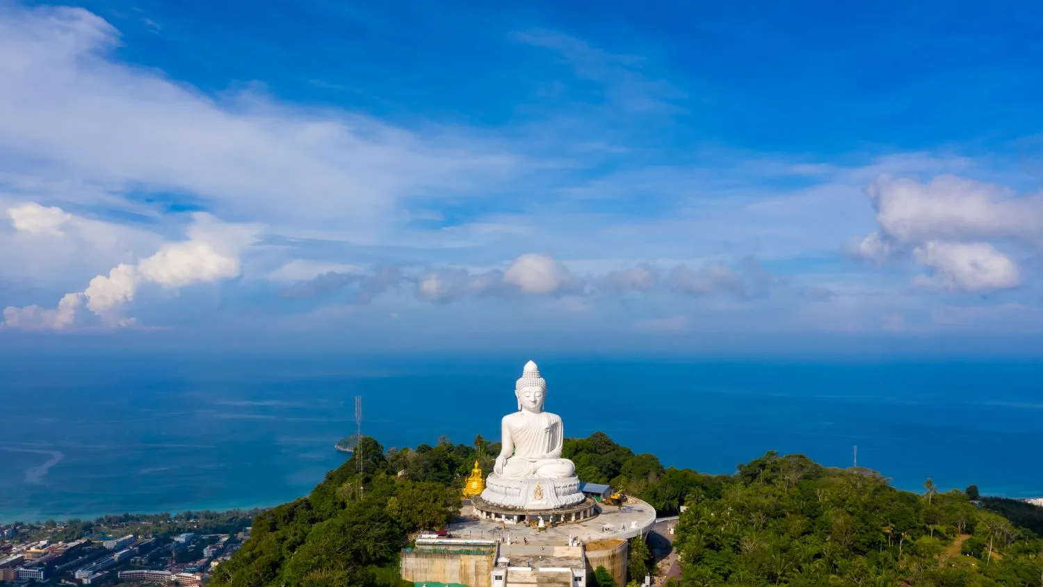 A white Buddha statue facing the open sea