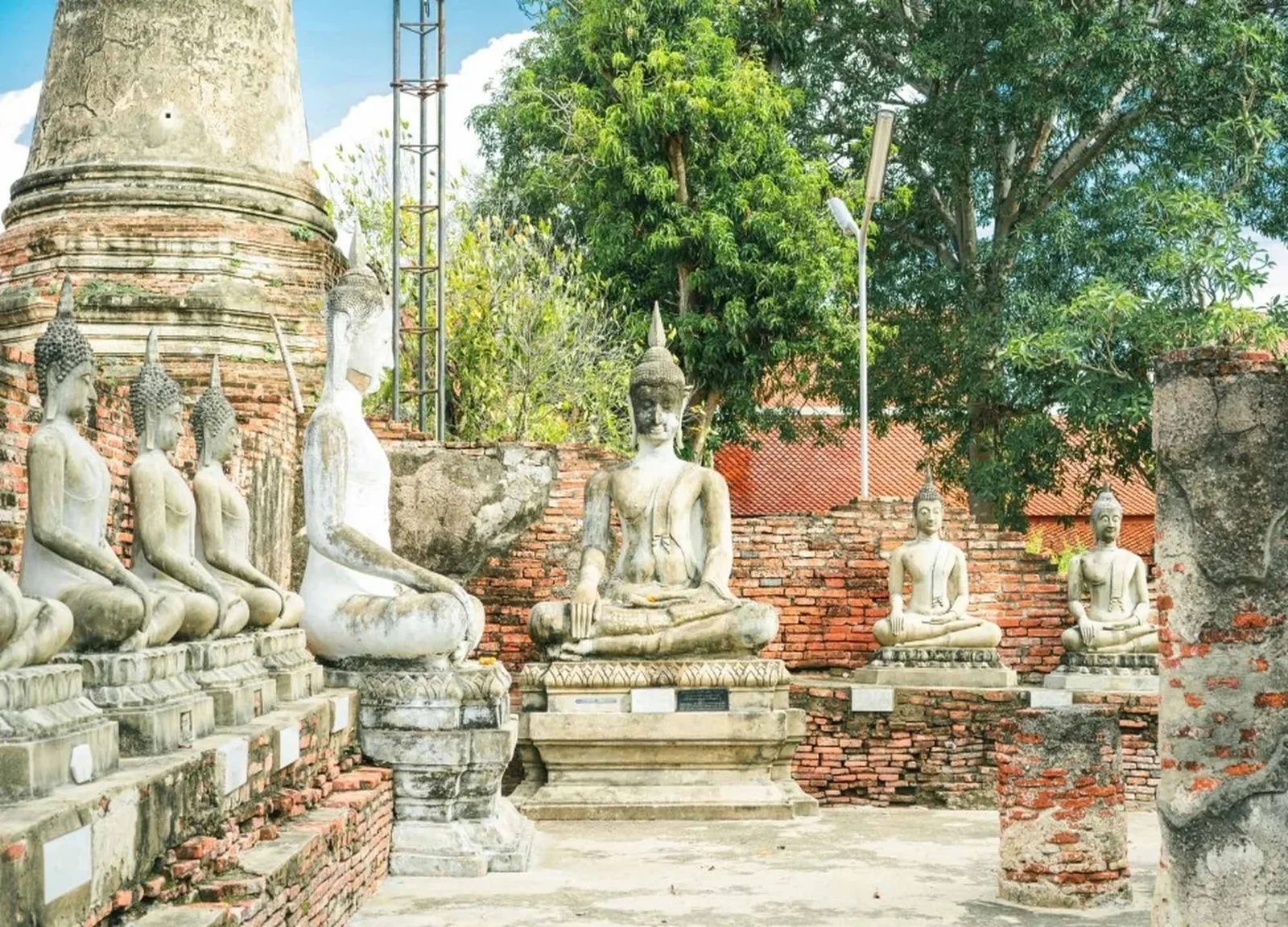 Buddha statues sit around the ancient chedi