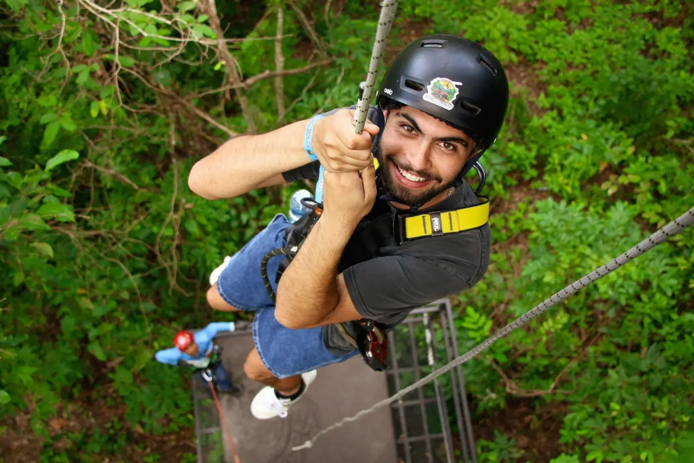 A traveler descends on a rope from a platform, seen from above
