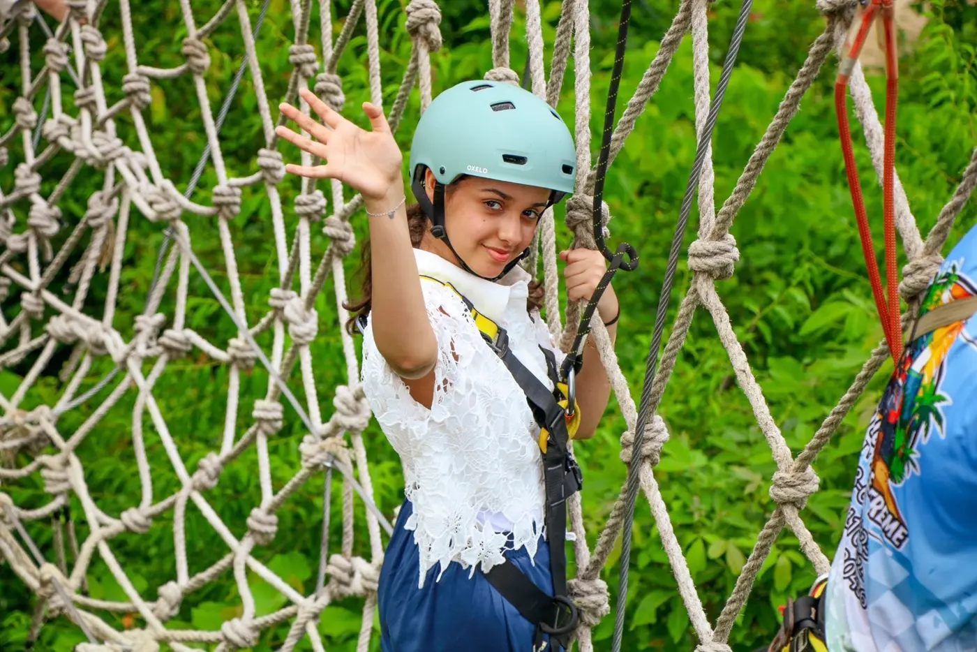 A girl on the walking net, holding onto the ropes