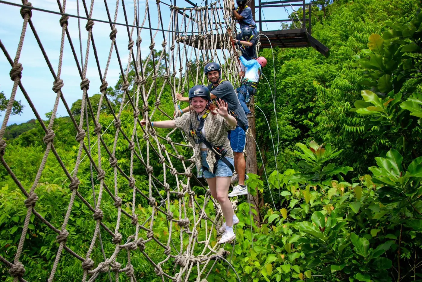 Two travelers on a rope-net bridge above the forest