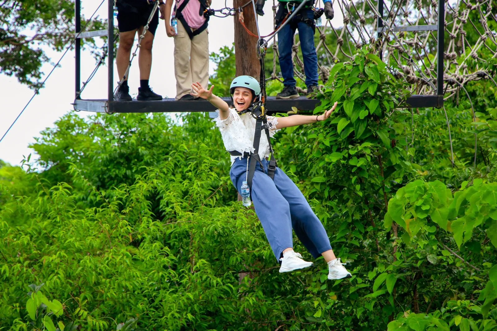 Gliding on a zipline with arms outstretched above the treetops at Jungle Extreme