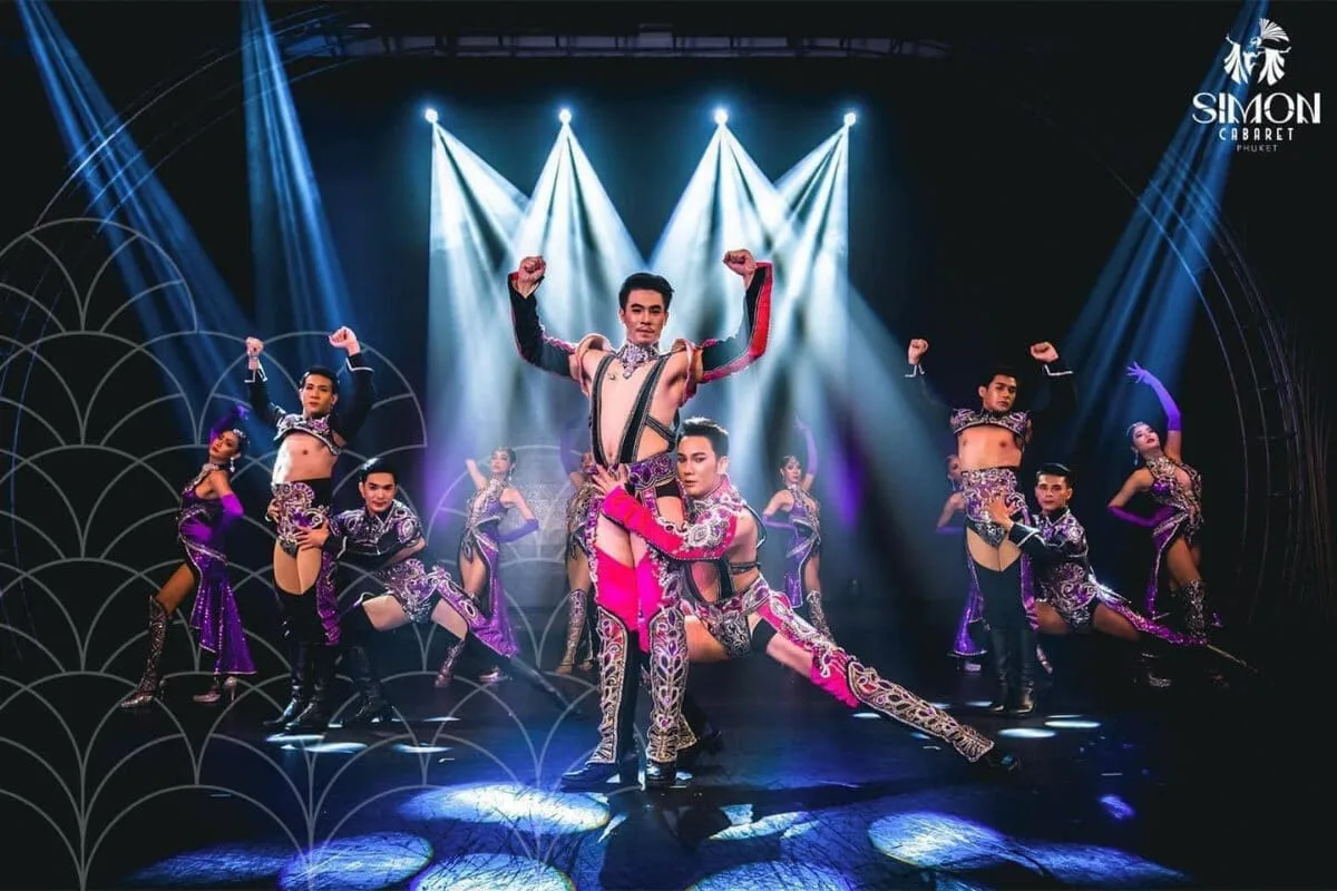 A number on stage with dancers and stage lighting, and a lead performer up front